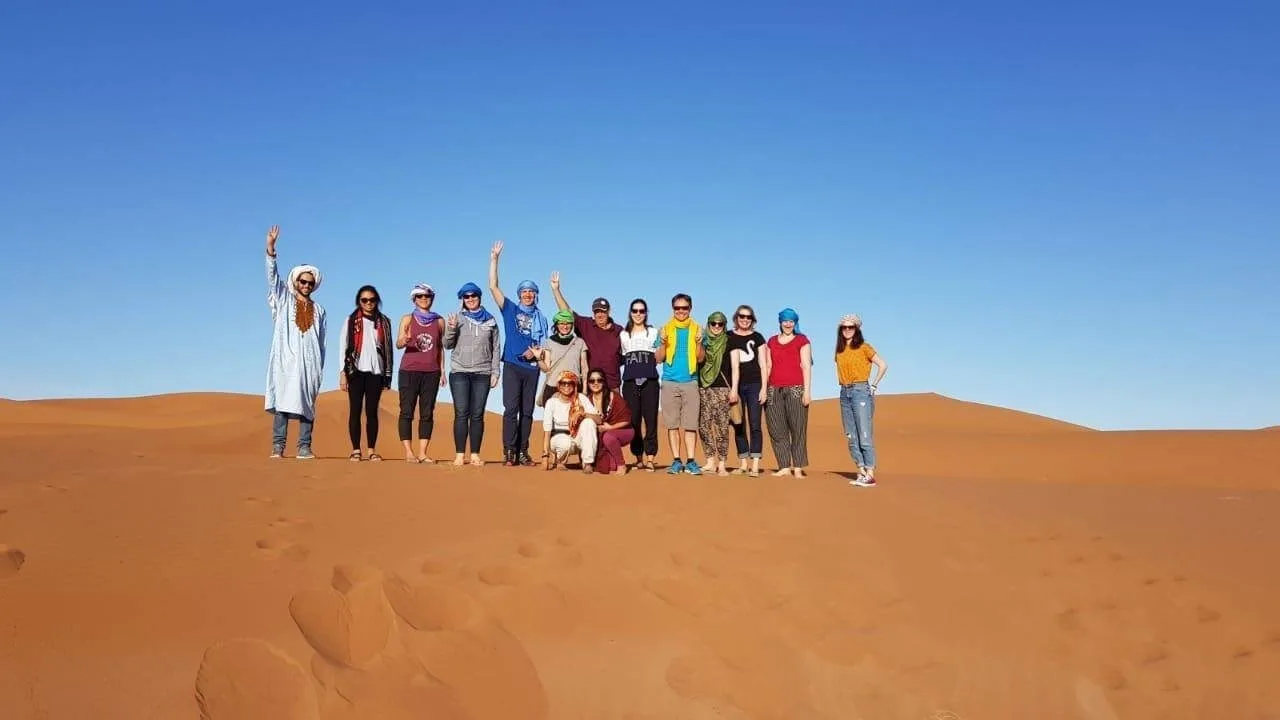 Marokko Travel guide and guests celebrating on the Sahara dunes near Merzouga